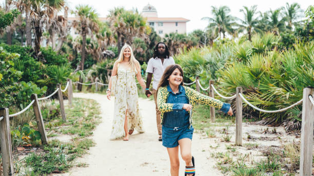 istock Attractive affluent mixed race couple with their joyful daughter walk on a beach boardwalk on vacation 1422673900
