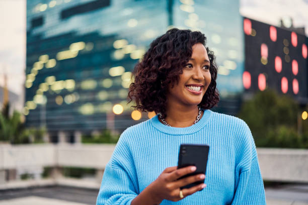 istock Happy black woman, smile on face and phone for text communication and online internet or web search. Girl in New York City road using smartphone social media app or gps system to find street location 1422681449