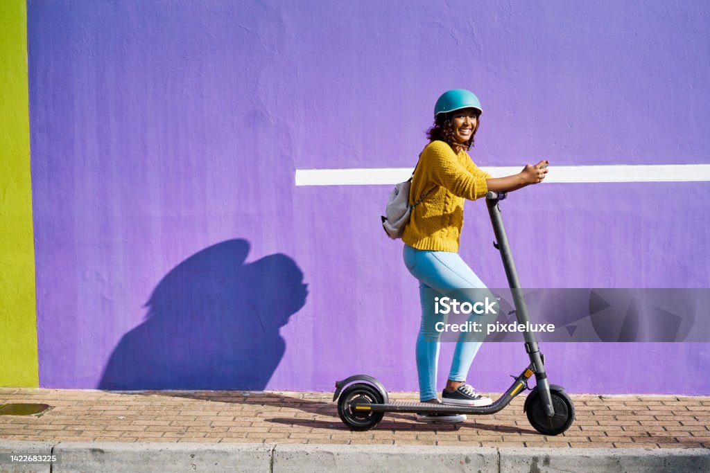 Woman, electric scooter and city travel for fashion student by building background with social media phone. Happy, cool model on eco friendly, environment carbon footprint and future energy transport Malay Quarter Stock Photo
