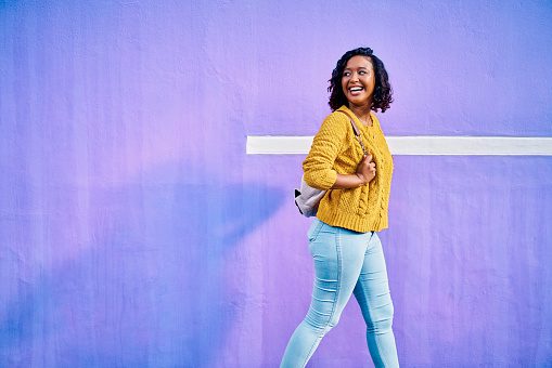 Happy, smile and woman from Guatemala walking with a positive energy, happiness and mock up. Young female walk and travel with excited mindset in front of a colorful and bright purple mockup wall