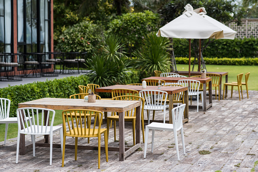 Table sets in outdoor cafes in beautiful green garden outside restaurant building