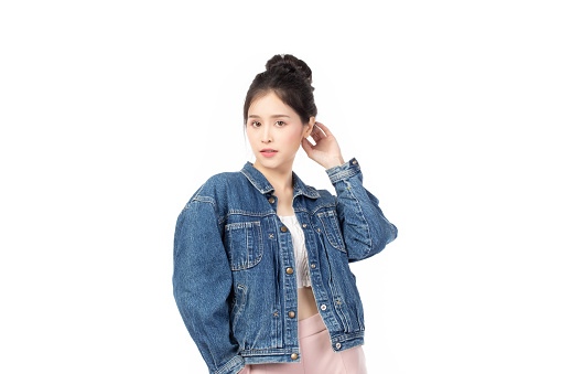 Portrait of beautiful asian woman model in white T-shirt, dressed in denim jacket posing while standing and looking at camera isolated on white background.
