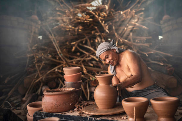 A senior man is using a potter's wheel to make pottery from wet clay. stock photo