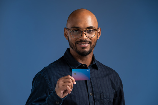 Portrait of businessman with credit card against blue background