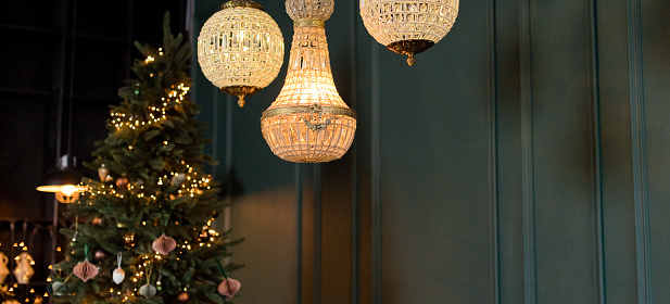 Bannner with round crystal chandeliers in loft interior with green wall and decorated Christmas tree