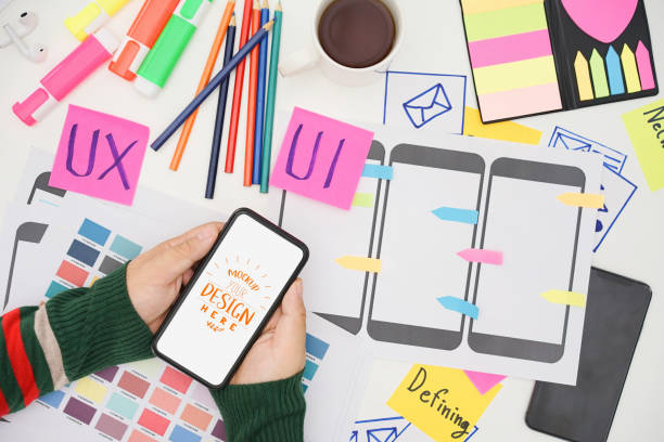 istock Creative UX UI designer hand holding mobile white screen mockup at working desk space. White screen for graphic montage. 1422702394