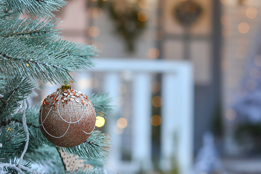 A beautiful golden ball on a Christmas tree on the thebackground of the Christmas porch of the house. Winter mood.