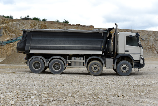 Large dump truck tipper driving in the dust in the quarry