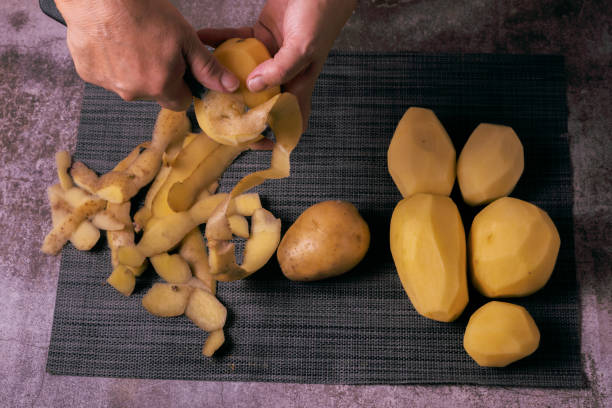 istock woman peeling potatoes with a knife and apron 1422713969