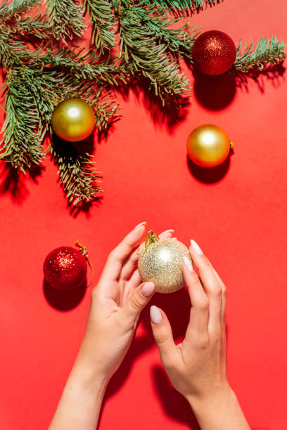 istock beautiful women's hands on a red background with Christmas tree branches and balls, hand care in winter.. Xmas New Year theme. 1422715962