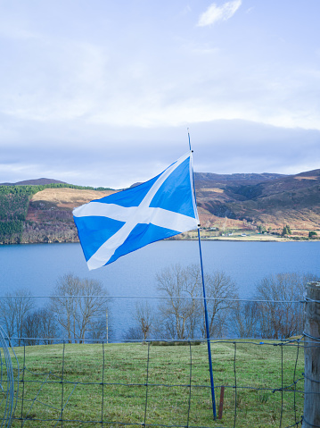 A Scottish national flag next to a loch.