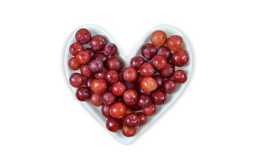 Fresh red grapes atop a heart shaped plate isolated on a white background. Contains clipping path around the heart plate.