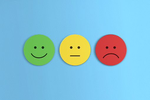 Three paper emoticons against a cheerful blue paper background.