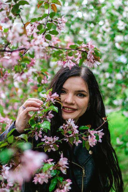 lifestyle'owy portret młodej uśmiechniętej pięknej kobiety z różowymi kwiatami jabłoni w deszczową pogodę. - meteorology elegance outdoors loving zdjęcia i obrazy z banku zdjęć