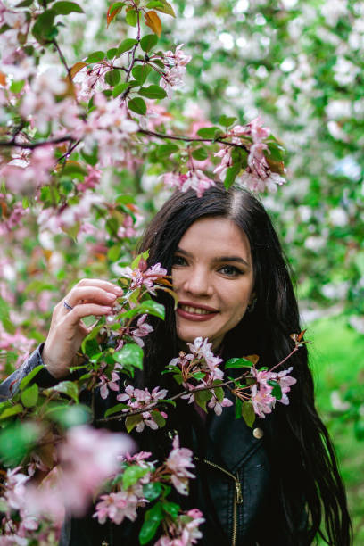 образ жизни портрета молодой улыбающейся красивой женщины с розовыми цветами яблони в дождливую погоду. - meteorology elegance outdoors loving стоковые фото и изображения
