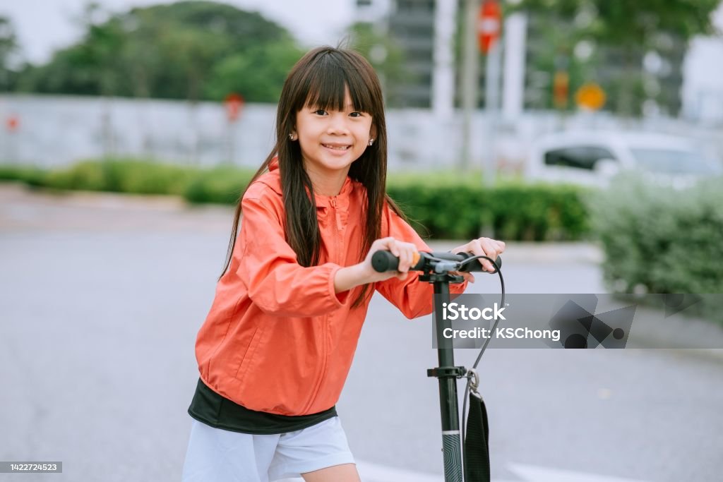 Happy Asian girl enjoy riding with her push scooter outdoor Electric Push Scooter, Child, Asia, Fun, Push Scooter 8-9 Years Stock Photo