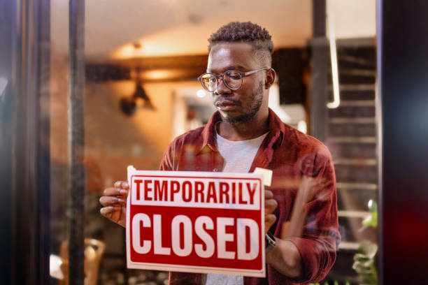 그의 가게에서 "일시적으로 닫힌"표지판을 들고있는 한 남자의 잘린 샷 - going out of business closed business closed for business 뉴스 사진 이미지