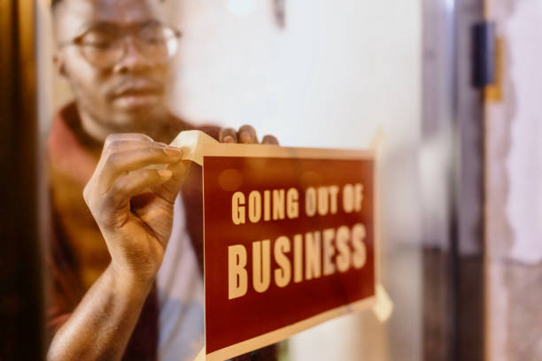 plan recadré d’un homme tenant une pancarte « fermer ses portes » dans son magasin - going out of business closed business closed for business photos et images de collection