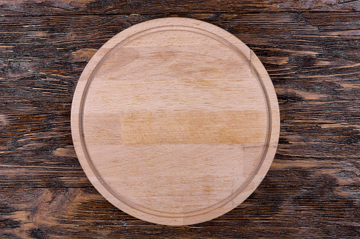 Empty kitchen board on a wooden background. Cutting board. Space for text. Top view.