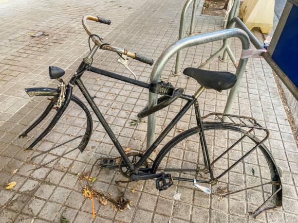Abandoned bicycle hooked to pole missing its wheels