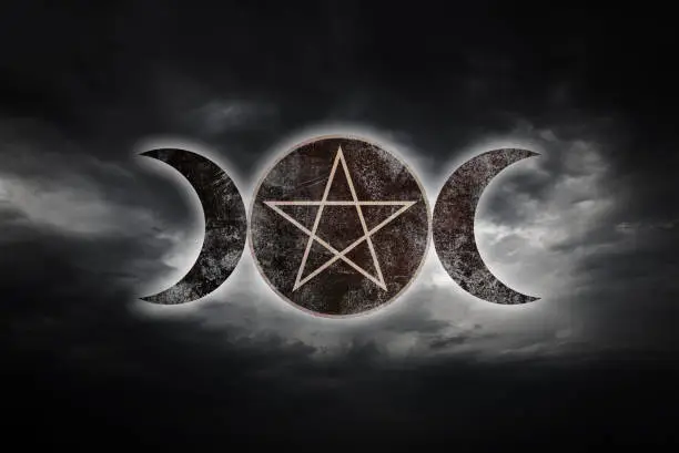 The Triple Goddess symbol of the waxing, full and waning moon over dramatic sky.