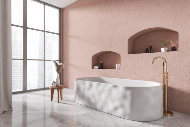 istock Light bathroom interior with tub, side table with bath accessories and window 1422736131