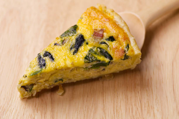 A slice of quiche with bacon and spinach