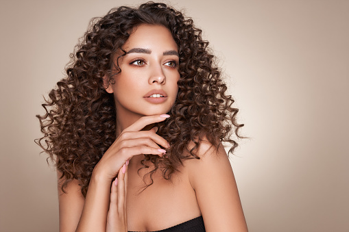 Beauty portrait of afro woman . Girl looking at camera. Elegant style. Curly hair. Brown eyes. Glamour makeup. Closeup photo.