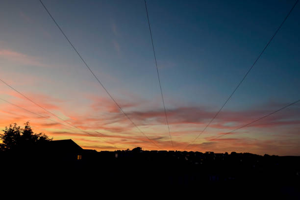 Cables over a sunset sky with residential houses
