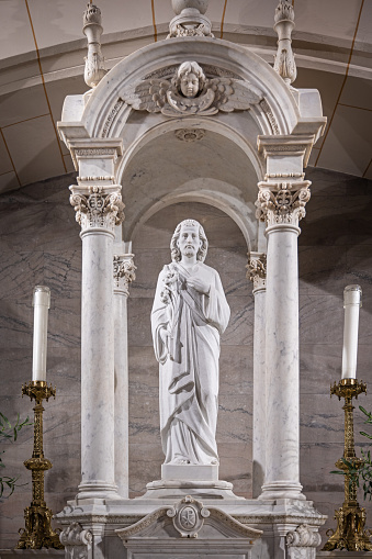 A majestic statue of the Virgin Mary is situated in a peaceful outdoor setting