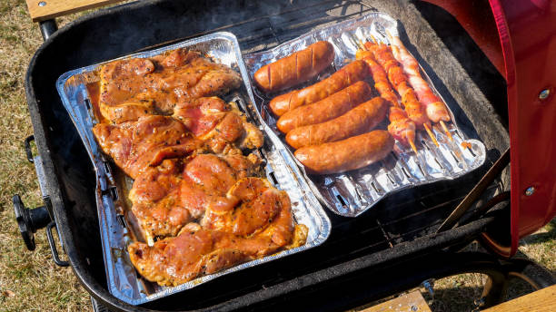 Close up of meat on a aluminum tray cooking on the grill
