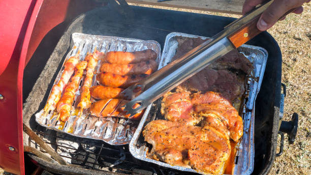 Close up of meat on a aluminum tray cooking on the grill
