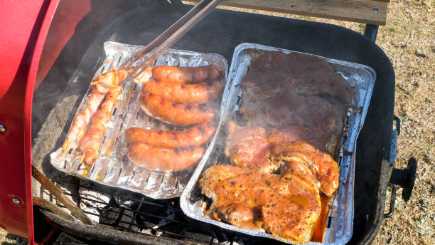Close up of meat on a aluminum tray cooking on the grill