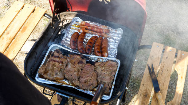 Close up of meat on a aluminum tray cooking on the grill