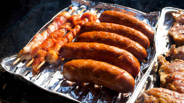 Close up of raw meat on a aluminum tray cooking on the grill
