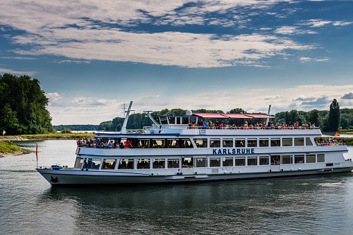 River cruise ship arriving on Danube in Bratislava with old town cityscape in background and other ships docked along embankment