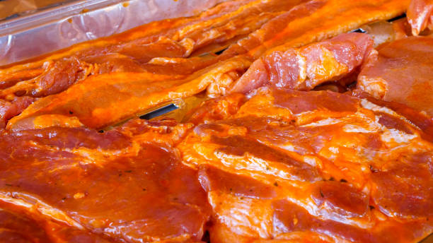 Raw meat laying on an aluminum tray prepared for grilling