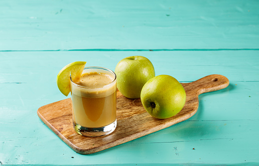 Apple and ginger juice with raw apples served in a glass isolated on cutting board side view healthy fruit juice