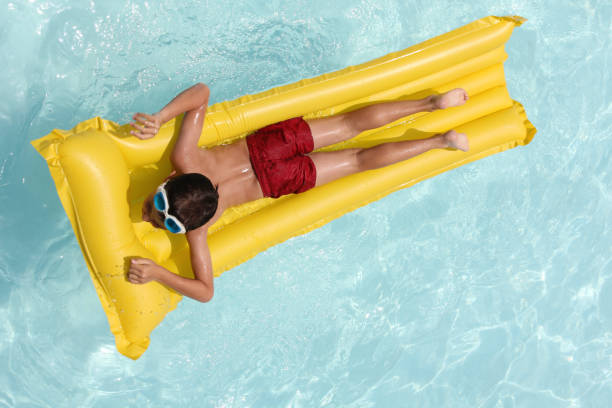 istock Young boy on a mat floating in the pool 1422750104