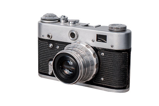 A young man taking a photo using a vintage film camera in a natural area