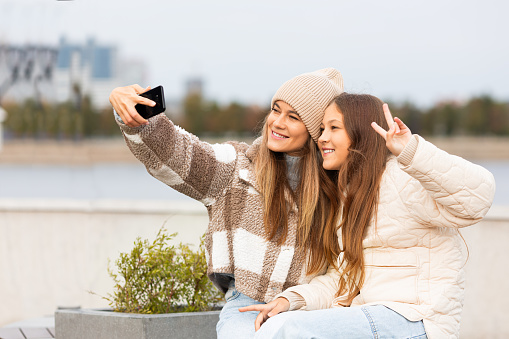 Trust and understanding between generations - mom and daughter taking a selfie during outdoor walking. Close-up photo.