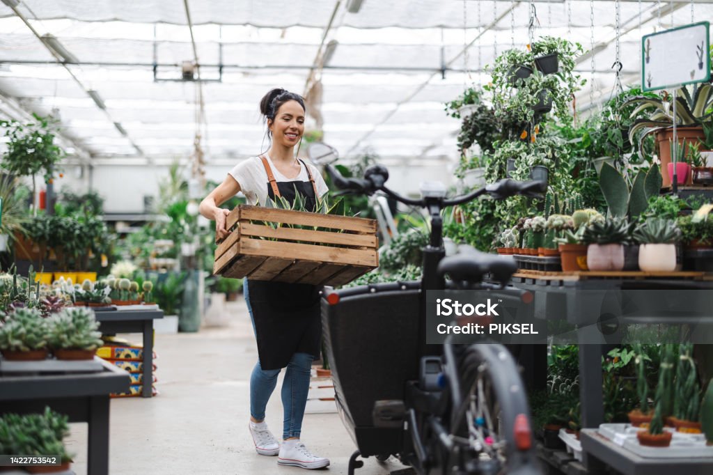 Shot of a young woman working with plants in a garden centre Cargo Bike Stock Photo