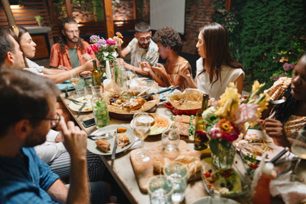Cheerful friends talking while enjoying dinner at dining table in party Friends and family having lovely garden dinner party in the summer, autumn gay dinner table stock pictures, royalty-free photos & images