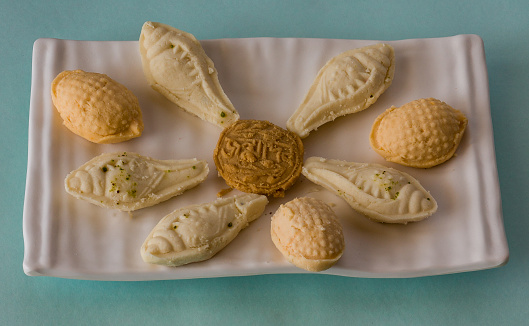 Top view of a plate with famous Bengali dessert or Indian sweet called Shankh Sandesh or Shondesh or Sondesh served during festivals like Diwali,Durga Puja and Dussehra in India.Blue Background.