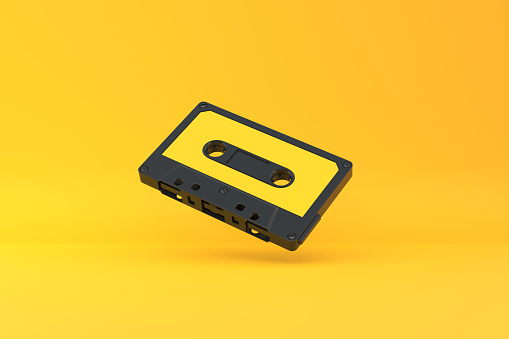 Vintage audio tape cassette on a yellow background. Front view with copy space. 3d rendering illustration