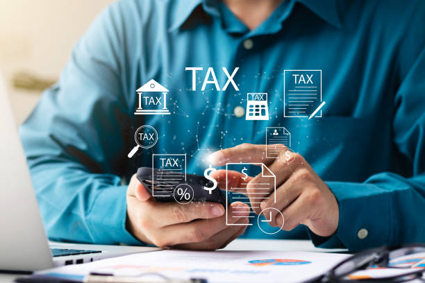 Businessman using his laptop computer and smartphone to fill out online personal income tax return form for tax payment, personal income tax calculation. stock photo
