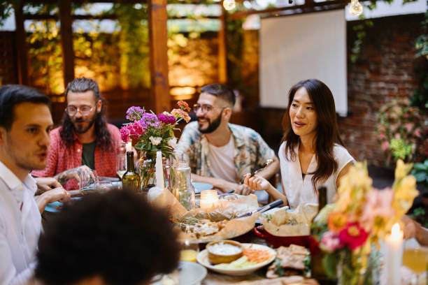 Family Enjoying An Outdoor Meal Together Friends and family having lovely garden dinner party in the summer, autumn gay dinner table stock pictures, royalty-free photos & images