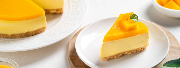 istock Delicious glazed mango no baked cheese cake with fresh diced mango pulp topping on bright table background. 1422767955