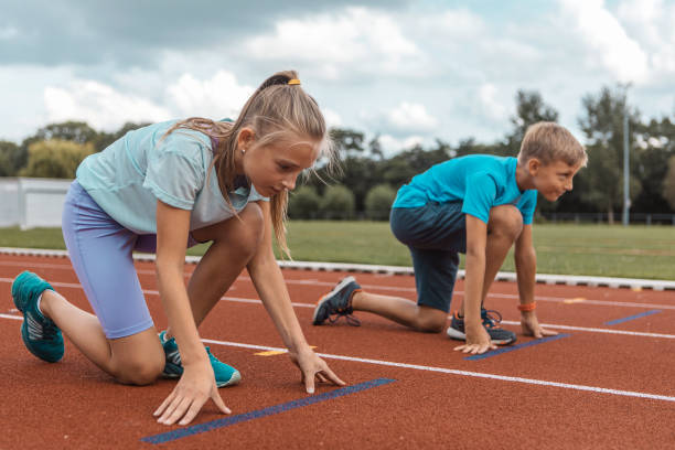 Two athletic children working hard on the running track stock photo
