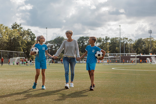 Beautiful blonde soccer mother football coach with her son and daughter during a training session at the football pitch